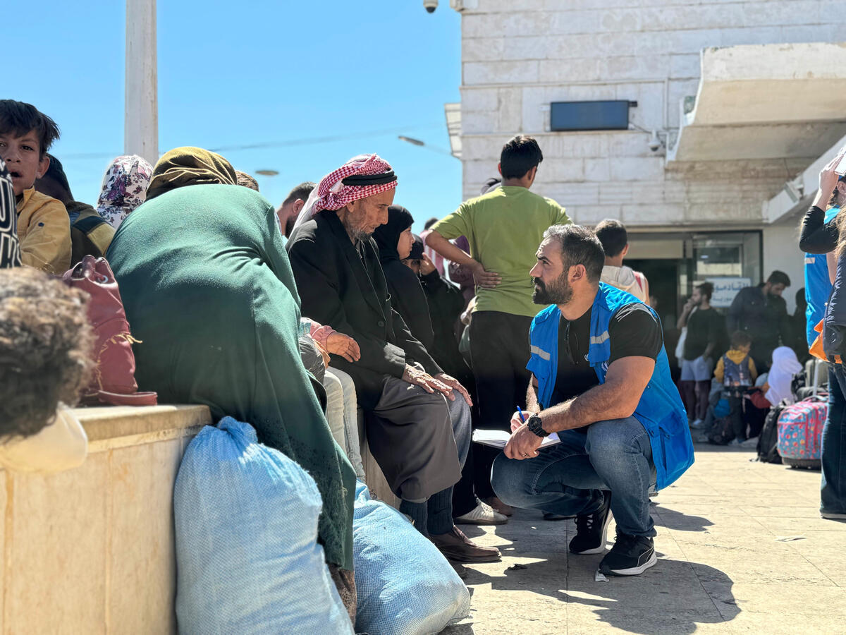 A UNHCR staff member talks to families arriving from Lebanon at the Jdaidet Yabous border crossing in Syria. A UNHCR staff member talks to families arriving from Lebanon at the Jdaidet Yabous border crossing in Syria.