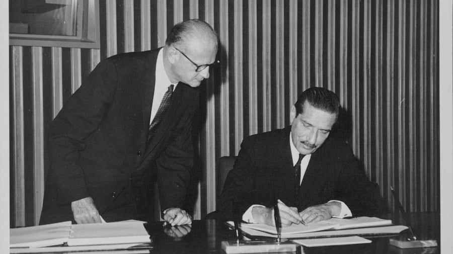 Mario Amadeo of Argentina signs the final act of the Convention on the Reduction of Statelessness on behalf of his country. Black and white photograph of a man signing the final act of the Convention on the Reduction of Statelessness.