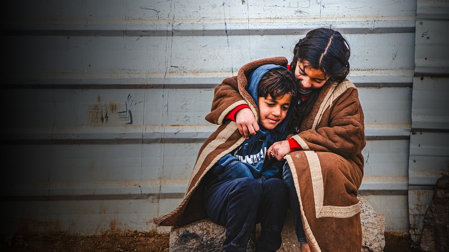 Syrian refugees Batool and her brother Abdulaziz A young Syrian refugee wraps herself and her younger brother in a blanket as they sit outside in the cold in the Zaatari refugee camp.