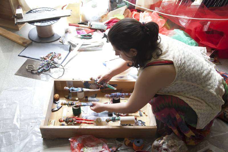 Heba works on a sculptural piece using string, dolls, newspaper clippings and other materials. 