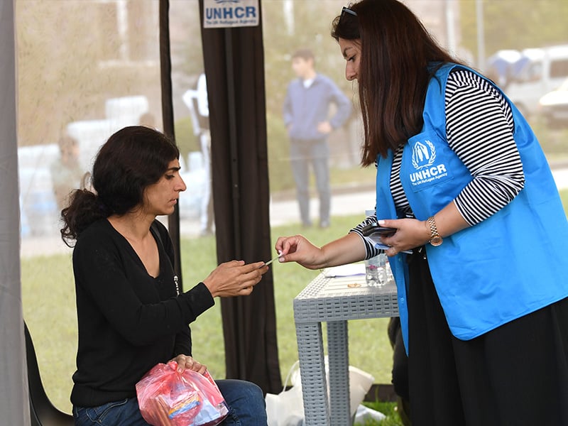 Armenia. Refugees arrive in Armenian border town. Arevig, UNHCR staff member, hands over a UNHCR leaflet with Hotline information and provides counseling