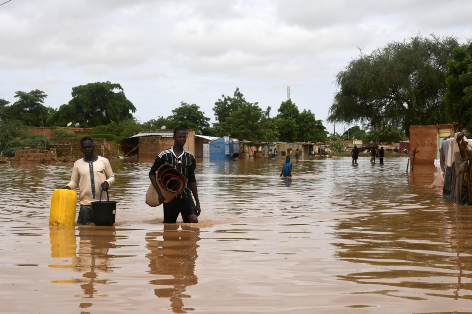 Des personnes transportent des effets personnels dans une rue inondée par le fleuve Niger dans le quartier de Kirkissoye à Niamey, au Niger le 27 août 2020. © AFP/Boureima Hama