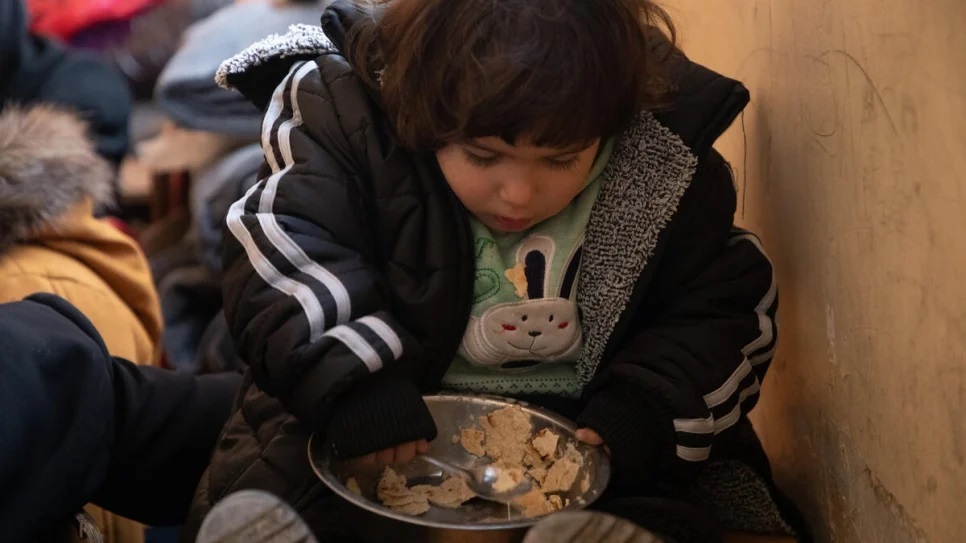 A young girl eats some bread at the school in Salahadin now hosting dozens of families from Aleppo displaced by the earthquakes_UNHCR_Hameed Maarouf