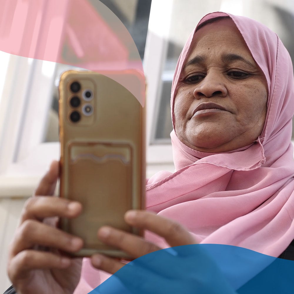 A Sudanese refugee interacts with her smartphone as she navigates the new onboarding tool provided by UNHCR. This digital tool empowers new arrivals to easily request a registration appointment. UNHCR/Pedro Costa Gomes.