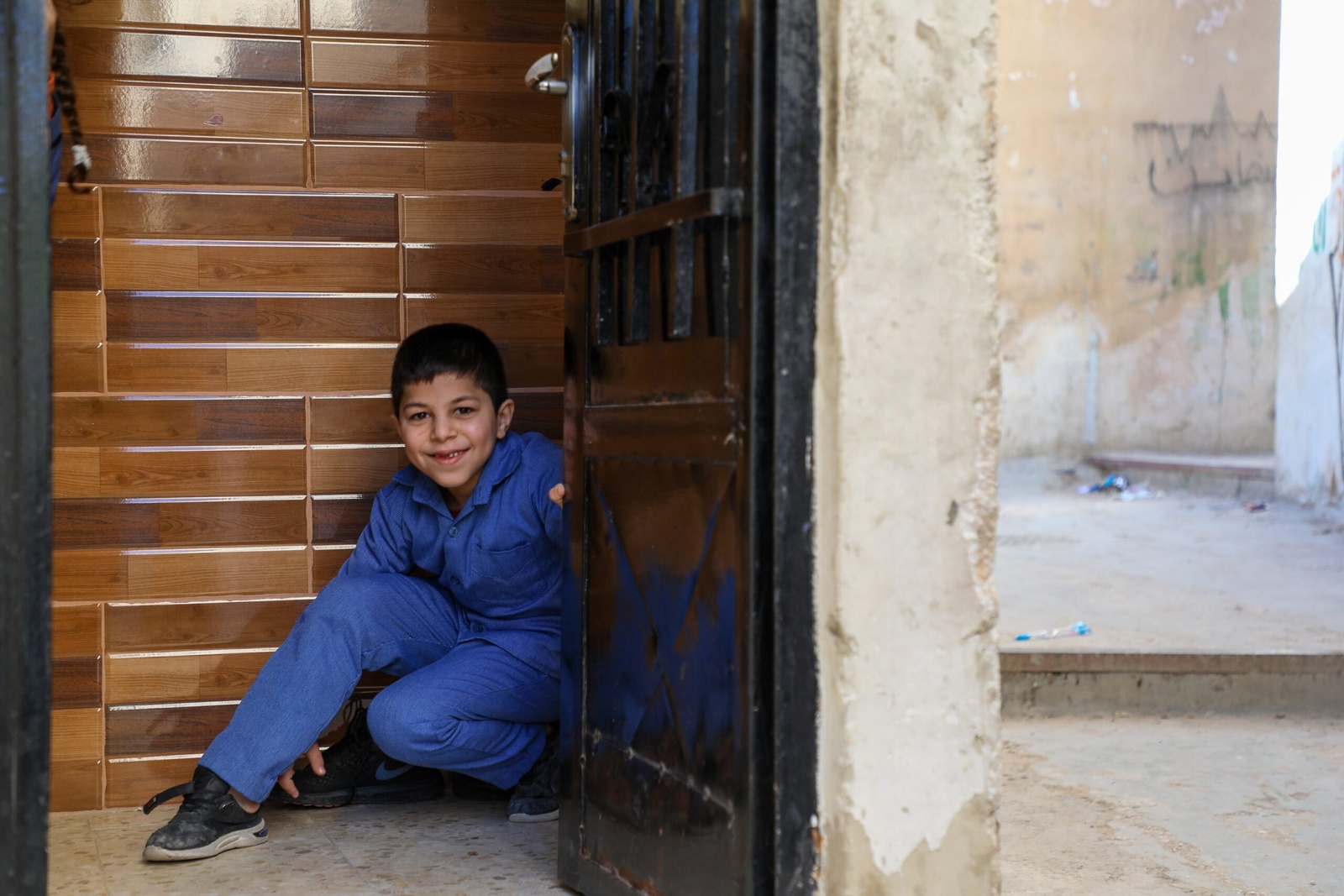 Jameela 的最年幼的兒子 Ahmed 今年 8 歲，他在他們位於約旦安曼的家門前。 © UNHCR