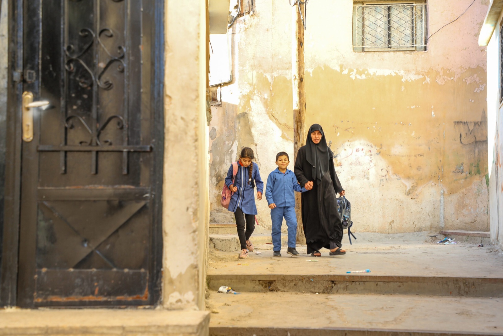 在學校因近日疫情嚴重而關閉前，10 歲的 Aisha 和 8 歲的 Ahmed 及他們的姨姨 Huda 一起走路回家。 © UNHCR/Lilly Carlisle