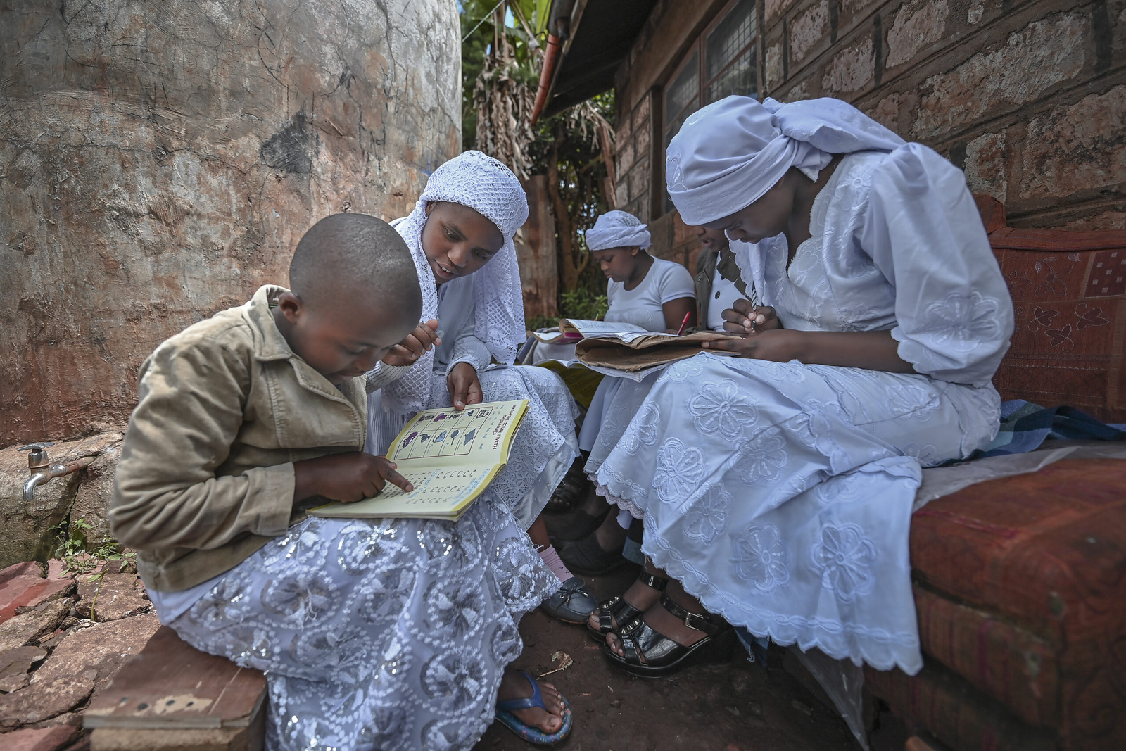 Nosizi Reuben（左二）在位於肯亞Kinoo的家門外，協助她的姊妹學習。 © UNHCR/Anthony Karumba