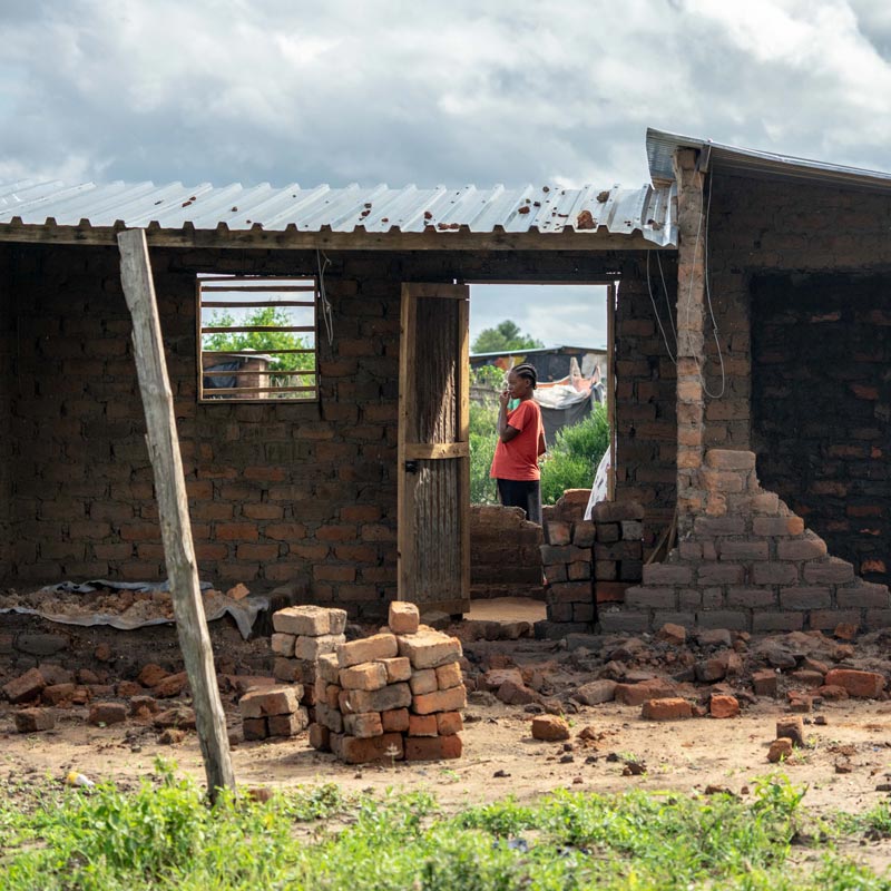 A woman surveys the damage to one of the estimated 2000 homes damaged when Cyclone Idai hit Tongogara Refugee Camp in Chipinge district in south-east Zimbabwe.