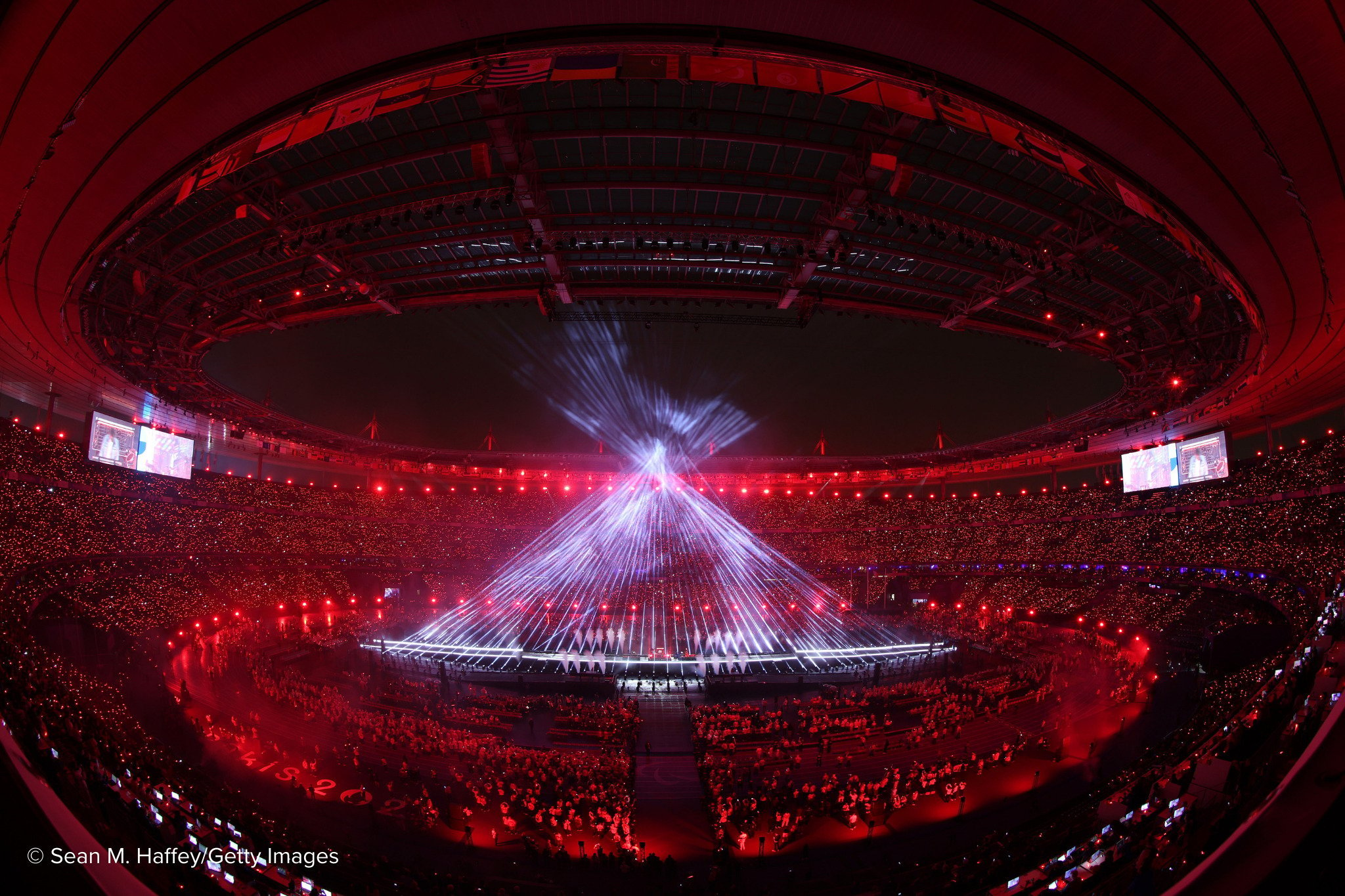 Beams of white light form a giant cone in the centre of a darkened stadium as part of a light-show.