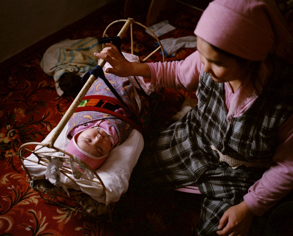 Een vrouw schommelt haar acht maanden oude baby in zijn wieg, Tastubek, Kazachstan. © Laurent Weyl/Panos Afbeeldingen