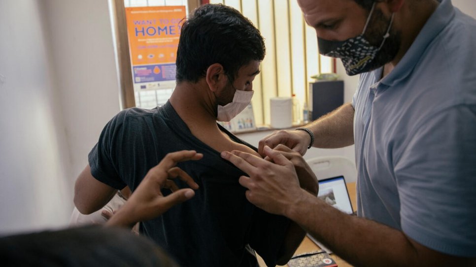 Nikola Kovačević kijkt naar de verwondingen van een Afghaanse asielzoeker die vanaf de grens werd teruggestuurd. © UNHCR/Vladimir Zivojinovic