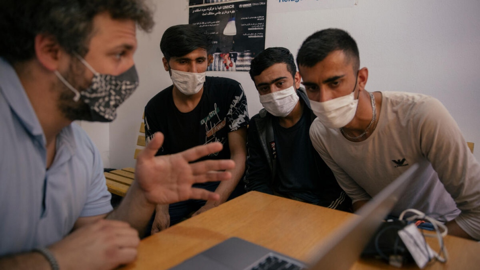 Nikola Kovačević praat met twee Afghaanse asielzoekers via een tolk in een opvangcentrum in Adasevci. © UNHCR/Vladimir Zivojinovic