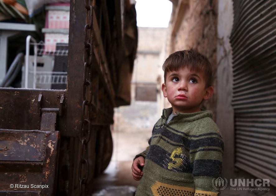 Syria. A Syrian child looks up as relatives load belongings onto a truck as they prepare to leave the town of Binnish