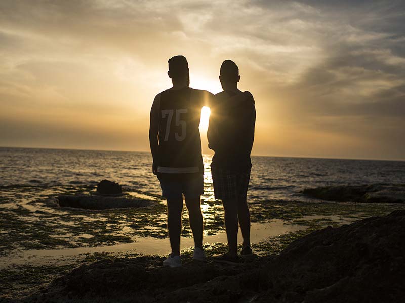 Two men at a beach at sunset