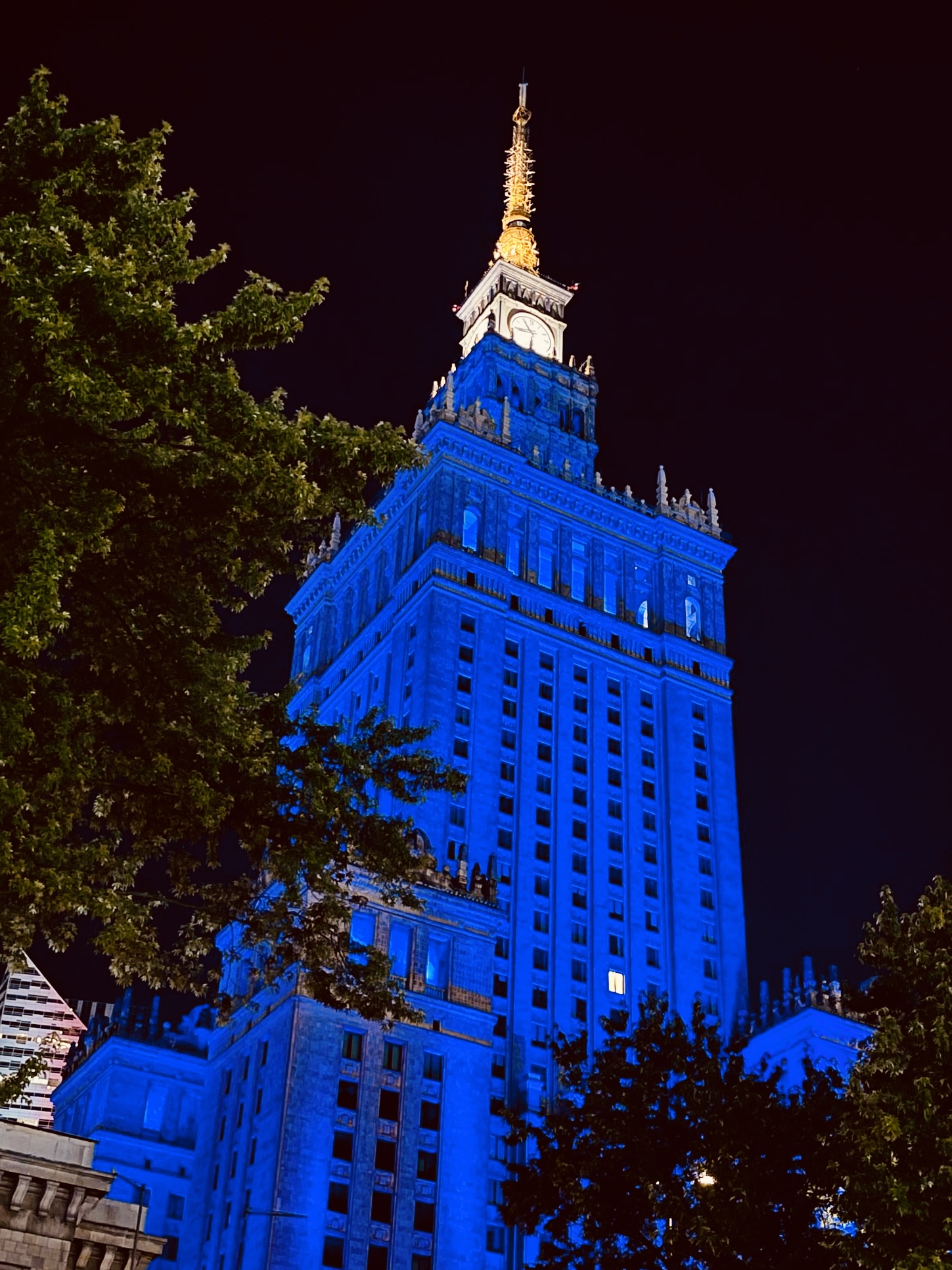 A high rise building lit up in blue with a white point