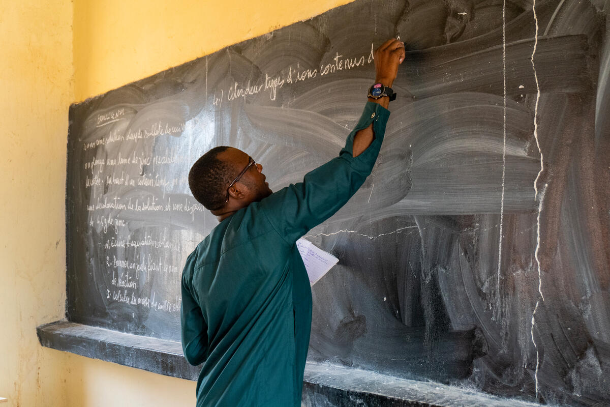 A man writes on a blackboard.