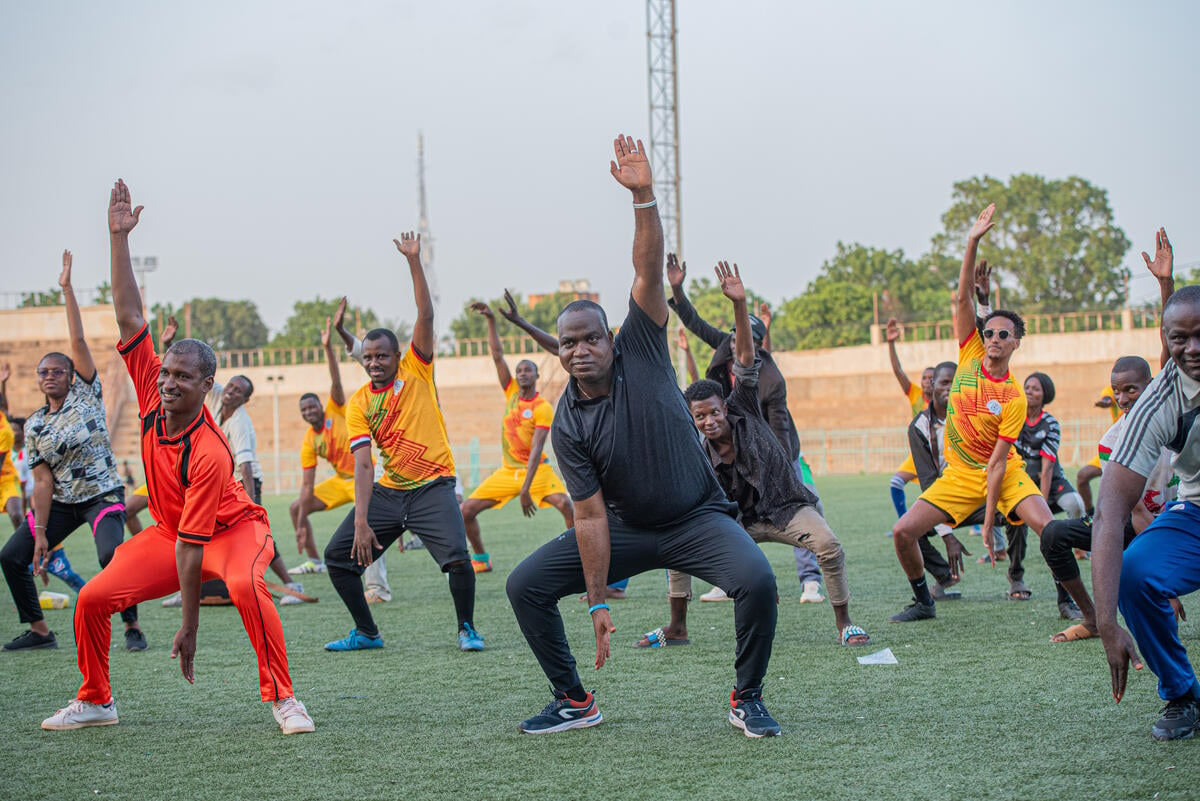 A group of refugees along with UNHCR staff and partners do an outdoor aerobics class