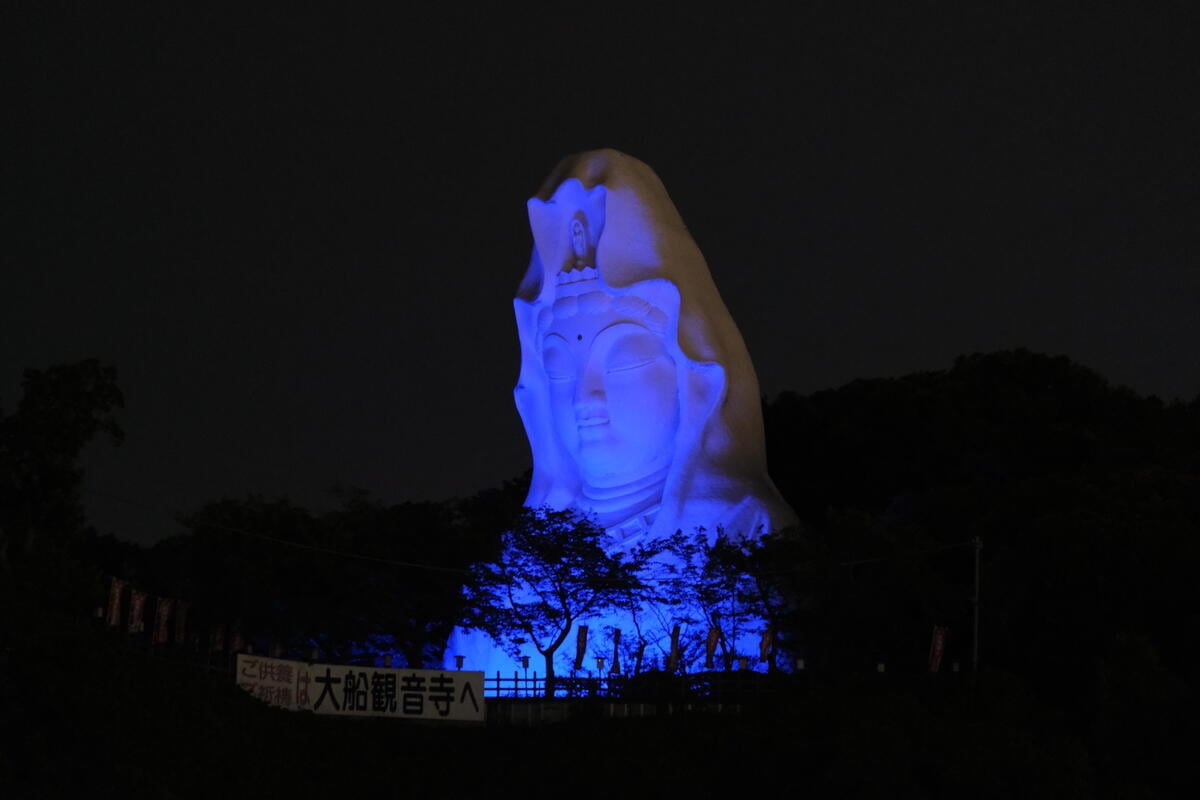 A large statue of the Buddhist goddess of mercy lights up in UNHCR blue.