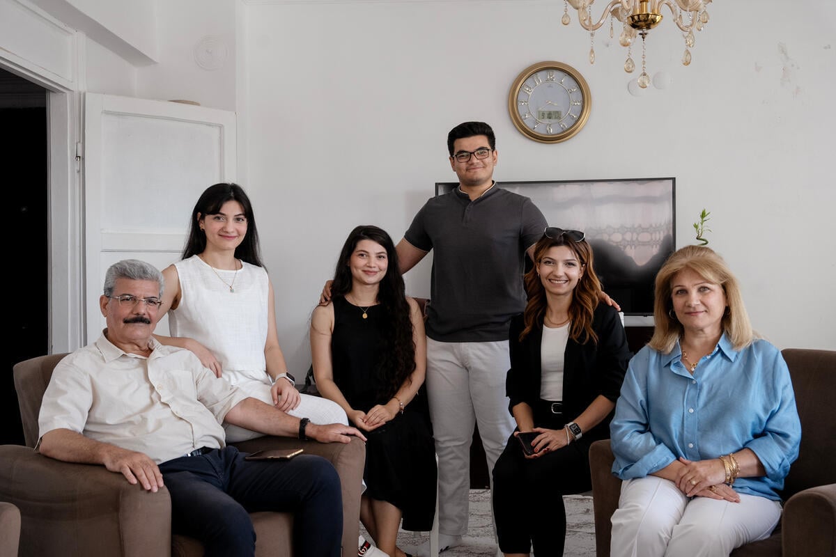 A family of six pose in a living room.