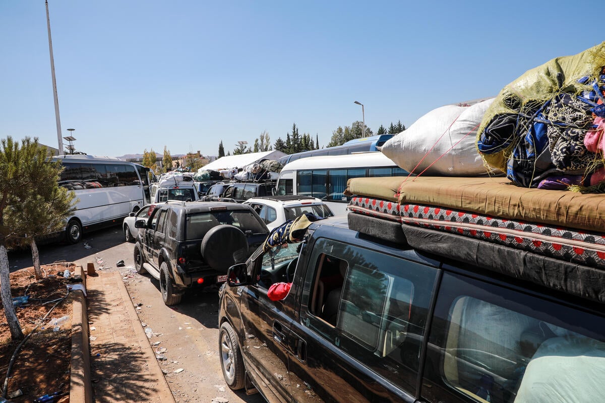 Vehicles piled with belongings queue in traffic.