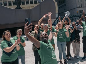 Un groupe de personnes souriantes et enthousiastes prend un selfie à Chicago lors des célébrations de la Journée mondiale des réfugiés.