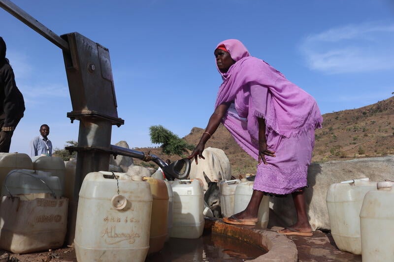 A woman fills containers with water from a standpipe in a village in Central Darfur.