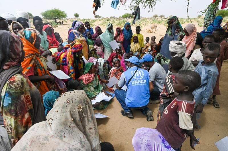 UNHCR staff members are surrounded by a crowd of Sudanese refugees in Chad.