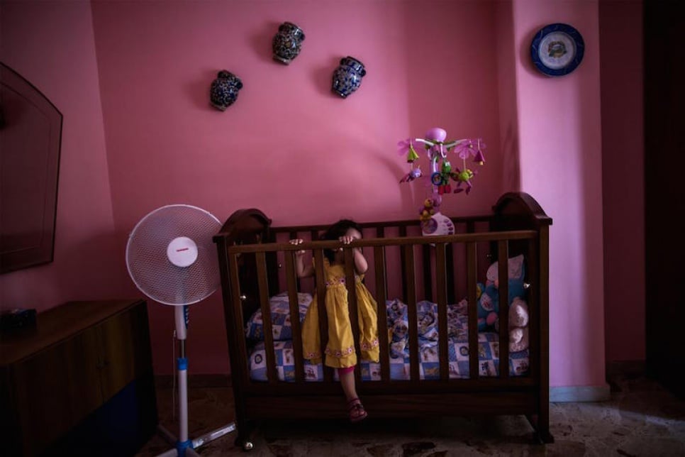 Alberto's youngest daughter plays in her cradle at the family's apartment in Catania.